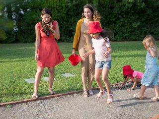 A joyous family experience in a lush Portugal park, featuring playful activities between young girls and adults.