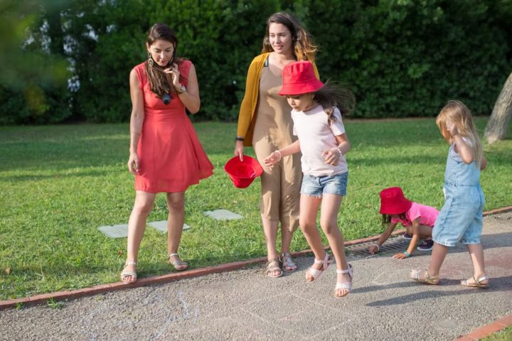 A joyous family experience in a lush Portugal park, featuring playful activities between young girls and adults.