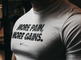 Close-up of a muscular man in the gym wearing a t-shirt with an inspiring fitness message.